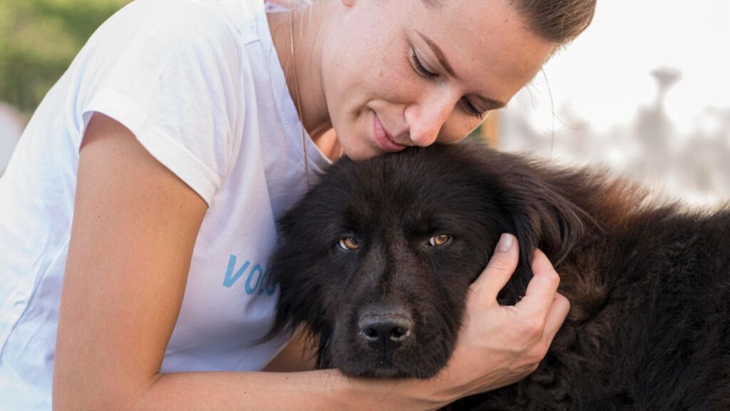 women hugging black dog